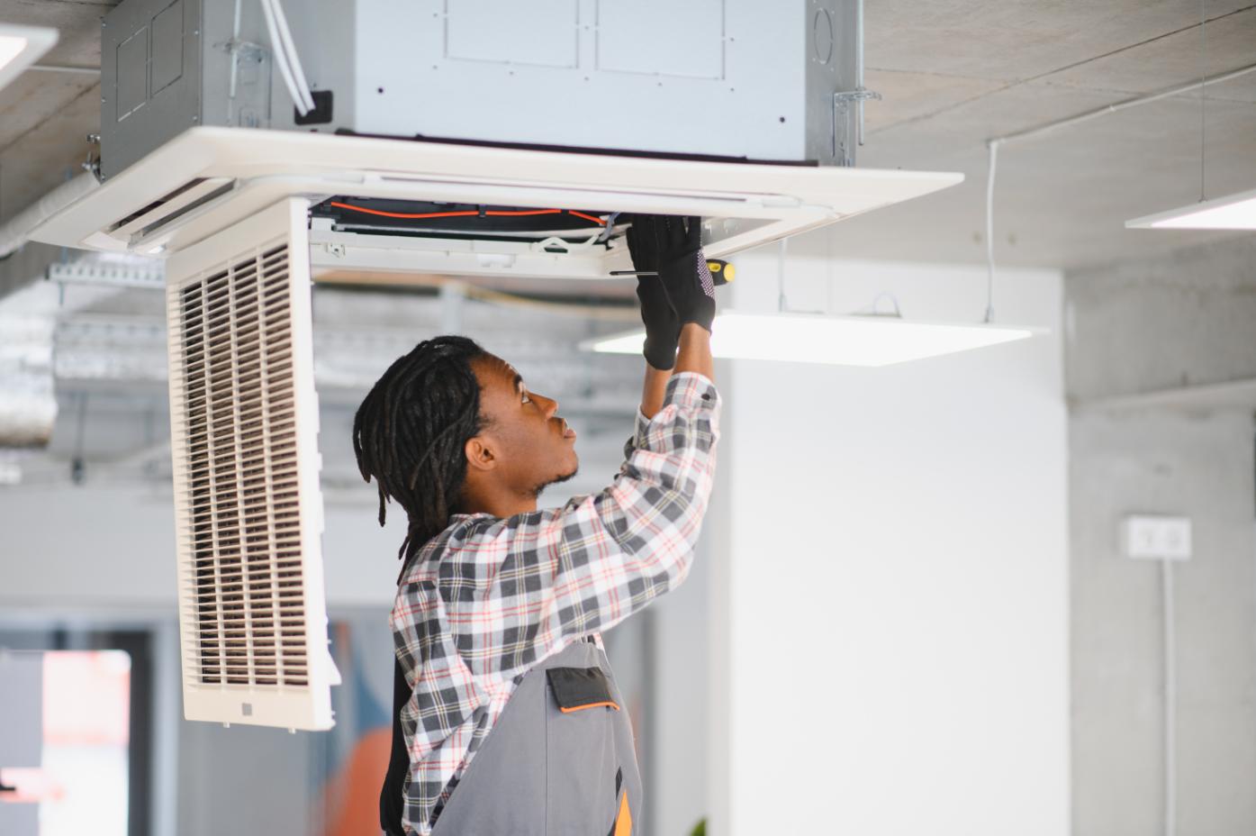 Technician repairing ceiling-mounted AC unit